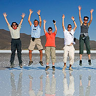 Tourists posing for camera while jumping in the air on the salt flat Salar de Uyuni, Altiplano, Bolivia