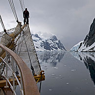 Sailing ship with man on bowsprit looking into the Lemaire Channel / Kodak Gap, Antarctica
