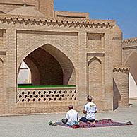 Two Turkmen praying on carpet in front of Mausoleum of Hoja Yusuf Hamadani in the ancient historic city of Merv / Merw near Mary, Turkmenistan