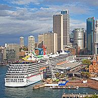 Cruise ship Carnival Spirit docked in the Sydney harbour and view over the city centre with its colonial buildings and modern skyscrapers, New South Wales, Australia