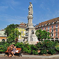 Tourists posing in front of statue of Walther von der Vogelweide at the Piazza Walther / Waltherplatz in Bolzano / Bozen, Dolomites, Italy 