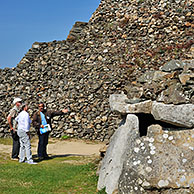 Tourists with guide visiting entrance to one of the chambers of the Cairn of Barnenez / Barnenez Tumulus / Mound, a Neolithic monument near Plouezoc'h, Finistère, Brittany, France  