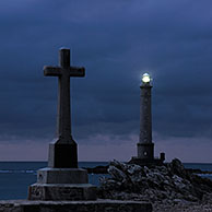 Cross and the lighthouse Phare de la Hague at night, Goury, Normandy, France