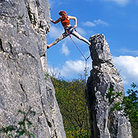 Female rock climber climbs cliff face at Mozet near Namur, Belgium