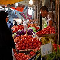 Iranian Muslim women wearing scarves buying vegetables and red tomatoes at food market booth in Gorgan / Gurgan, Golestan Province, Iran