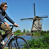 Cyclist and thatched windmill at Kinderdijk, a UNESCO World Heritage Site at South Holland, the Netherlands